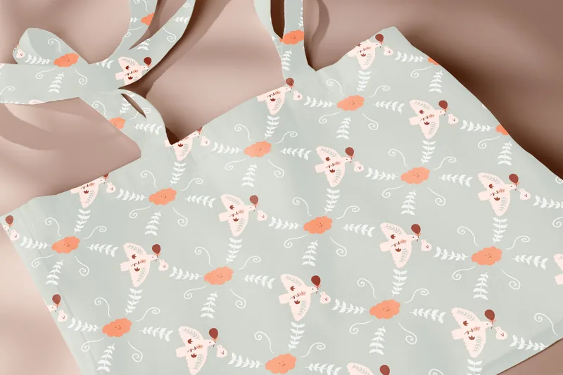 Close-up of a tote bag printed with a bird character pattern in sage green